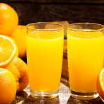 апельсиновый сок в стаканах, рядом лежат апельсины