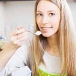 Девушка ест творог