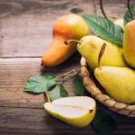 горка спелых груш в корзинке с листвой